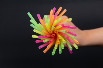 Swirl of bright colorful drink straws bunch in hand.
