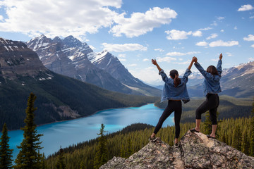 Couple female friends are enjoying the beautiful Canadian Rockies Landscape view during a vibrant sunny summer day. Taken in Peyto Lake, Banff National Park, Alberta, Canada. - obrazy, fototapety, plakaty