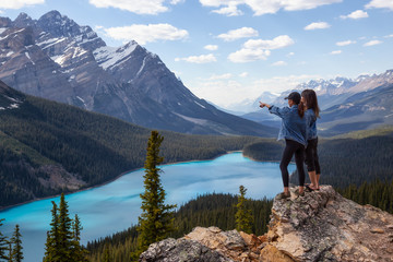 Naklejka na ściany i meble Couple female friends are enjoying the beautiful Canadian Rockies Landscape view during a vibrant sunny summer day. Taken in Peyto Lake, Banff National Park, Alberta, Canada.