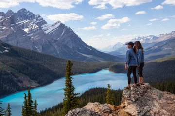 Naklejka na ściany i meble Couple female friends are enjoying the beautiful Canadian Rockies Landscape view during a vibrant sunny summer day. Taken in Peyto Lake, Banff National Park, Alberta, Canada.