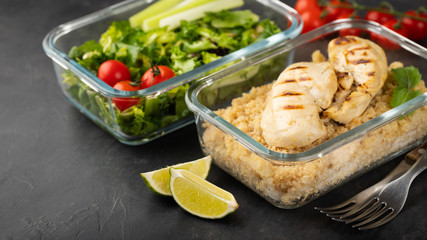 Healthy meal prep containers with quinoa, chicken breast and green salad overhead shot