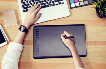 Businesswoman in office in casual shirt. Use computer for graphic designer and choose a color sample to match the publication.