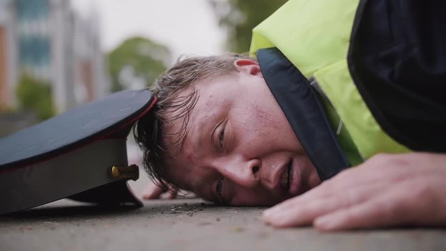 Traffic police caucasian middle age man officer in wet green reflection vest beaten and weary lying down on asphalt road on summer day