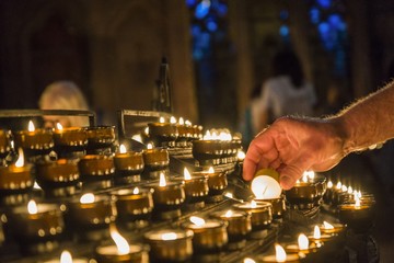 Mann zündet Opfer Kerze an in der Kirche 