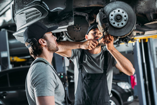 Professional Mechanics Repairing Car Without Wheel In Auto Repair Shop