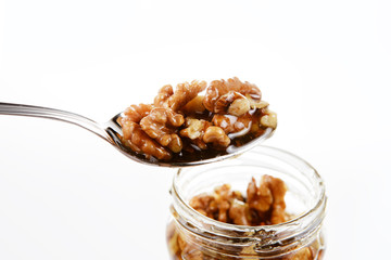 Jar of sweet honey and walnuts with silver spoon on a white background. Health and beauty concept.