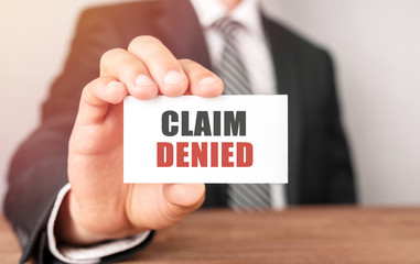 Businessman holding a card with text Claim Denied