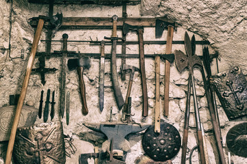 Wallpaper background of ancient medieval weapons hanged on a vintage stone and concrete wall....