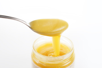 Jar of sweet honey with silver spoon on a white background. Health and beauty concept.