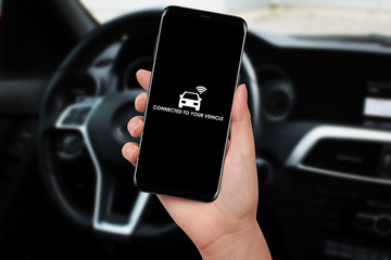 Woman connecting car with her smartphone and app using wifi. Wireless communication between smartphone and car.