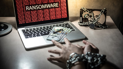 Hands tied up by chain and lock trying to grab dollar banknote and key on keyboard, Hard disk file...