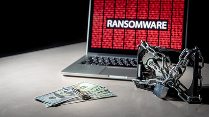 Hard disk file locked by chain and padlock with laptop computer monitor show red binary ransomware...