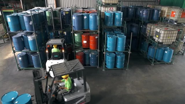 Fork-Lift Carrying 3 Barrels Passing Through Shelves Filled With Barrils 