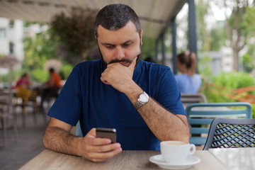 Worried man holding and using phone