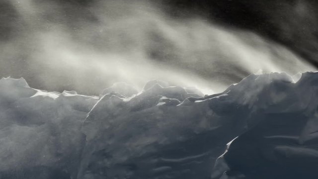 Cold winter wind blows snow over an embankment
