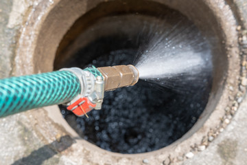 Schlauch spritzt wasser in den Schacht 