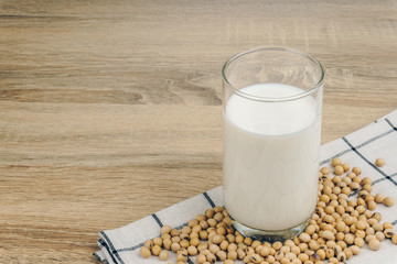 a glass of soy milk and a pile of soybeans on the wooden table.