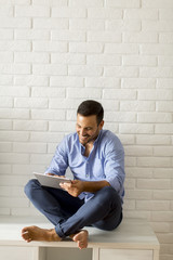 Young man using digital tablet in the room by wall