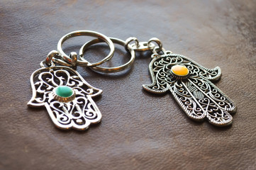Two key rings in the form of Fatima Hand on a brown leather background. Ancient symbol and traditional modern tourist souvenir of Tunisia