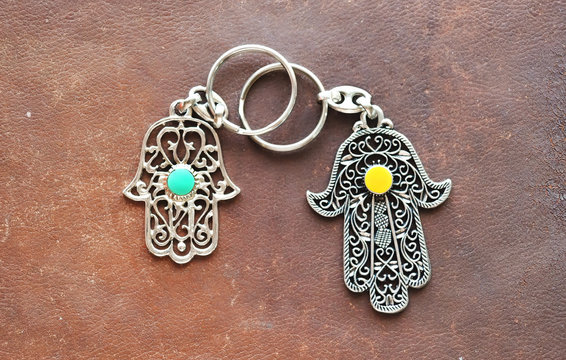 Two key rings in the form of Fatima Hand on a brown leather background. Ancient symbol and traditional modern tourist souvenir of Tunisia