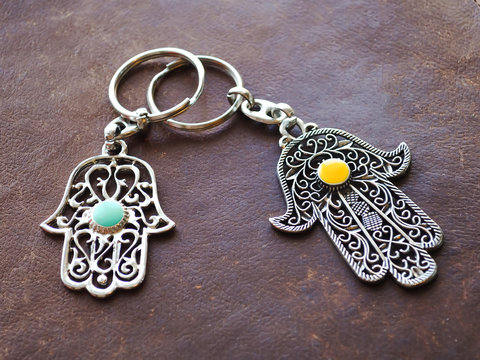 Two key rings in the form of Fatima Hand on a brown leather background. Ancient symbol and traditional modern tourist souvenir of Tunisia