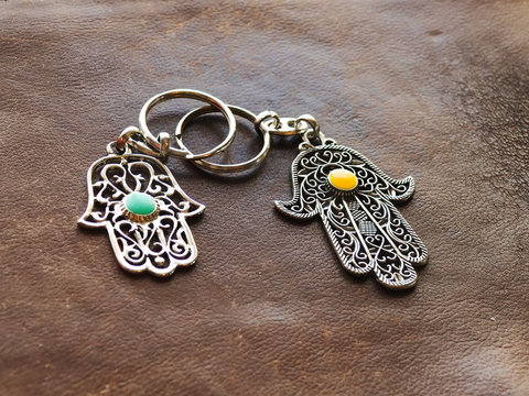 Two key rings in the form of Fatima Hand on a brown leather background. Ancient symbol and traditional modern tourist souvenir of Tunisia