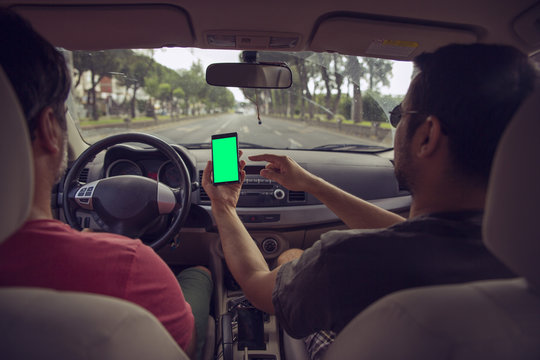 Mockup image of a hand holding and using green mobile phone screen in car