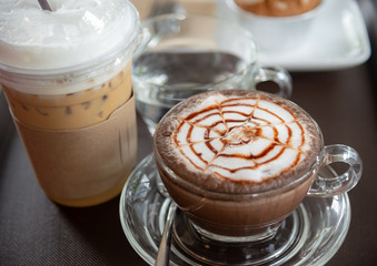 Cappuccino coffee with ice milk tea on wooden table