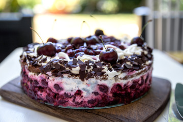 Selbstgebackene Schwarzwälderkirschtorte mit frischen Kirschen auf braunem Holzbrett