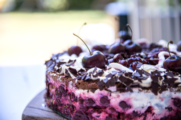 Selbstgebackene Schwarzwälderkirschtorte mit frischen Kirschen auf braunem Holzbrett