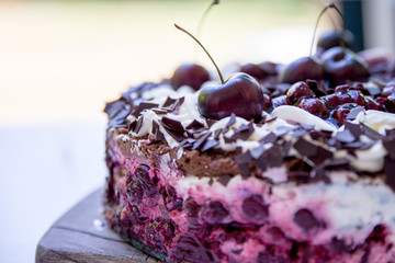 Selbstgebackene Schwarzwälderkirschtorte mit frischen Kirschen auf braunem Holzbrett