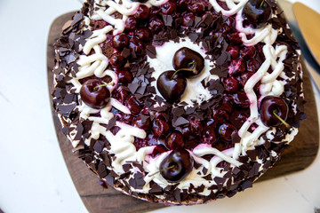 Selbstgebackene Schwarzwälderkirschtorte mit frischen Kirschen auf braunem Holzbrett