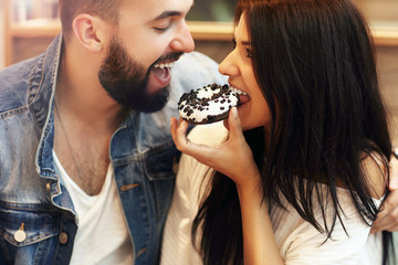 Romantic couple dating in cafe and eating donut