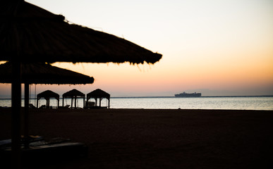 cargo ship at sea horizon through sunrise beach