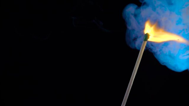 Burning match on a black background in slow motion