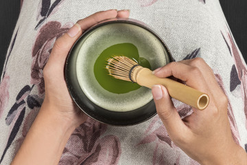 Whisking ceremonial green tea with chasen .Harmonic foamy Matcha cup of tea 
