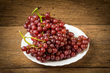 grapes seedless red on dish on old wood