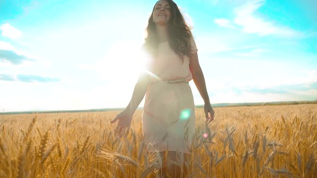 girl is walking along the wheat field nature slow motion video. Beautiful girl in white dress running nature freedom happiness hands to the side lifestyle on field at sunset light and the blue sky