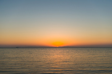 sunrise at sea with cargo ship on horizon
