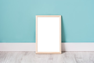 Frame mockup on white wooden floor and turquoise wall. Copyspace.

