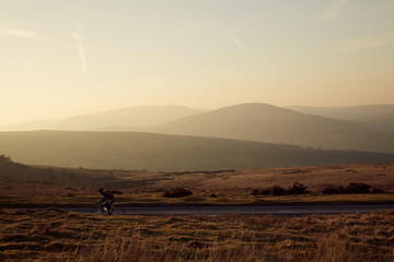 Cyclist riding at sunset in the Brecon Beacons, Wales.