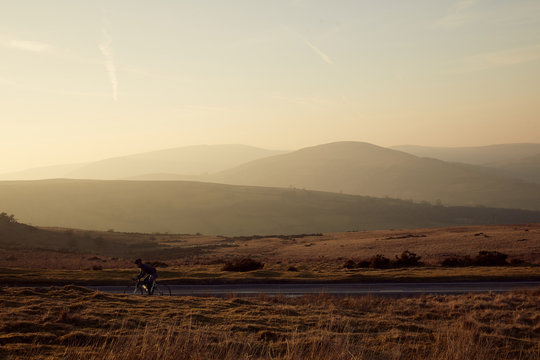 Cyclist Riding At Sunset In The Brecon Beacons, Wales.