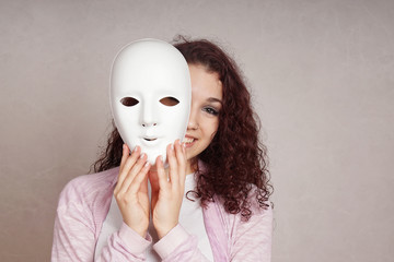 smiling young woman peeking from behind mask