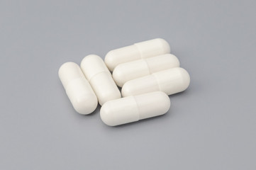 Large white pills on a gray background. In the center of the image.