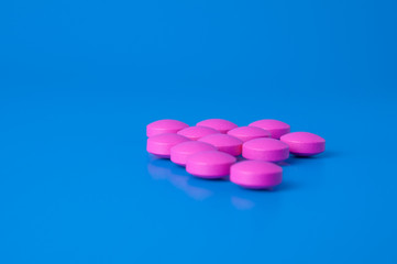 Obraz na płótnie Canvas Bright pink pills on a blue background.