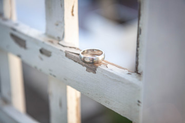 A groom's wedding ring on a wooden fence