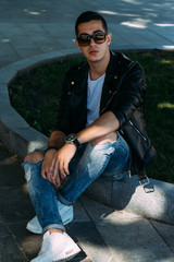 a young guy smokes around a tree in the city.bad habit.smoking in a public place