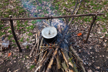 Cooking in old sooty cauldron on campfire at glade