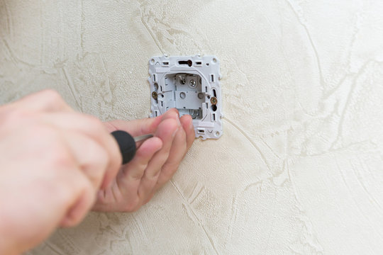 Male electrician puts on and repair an electrical outlet