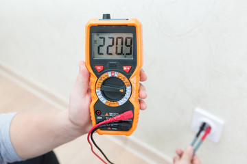 Close-up of man measuring and cheking power supply voltage with digital multimeter